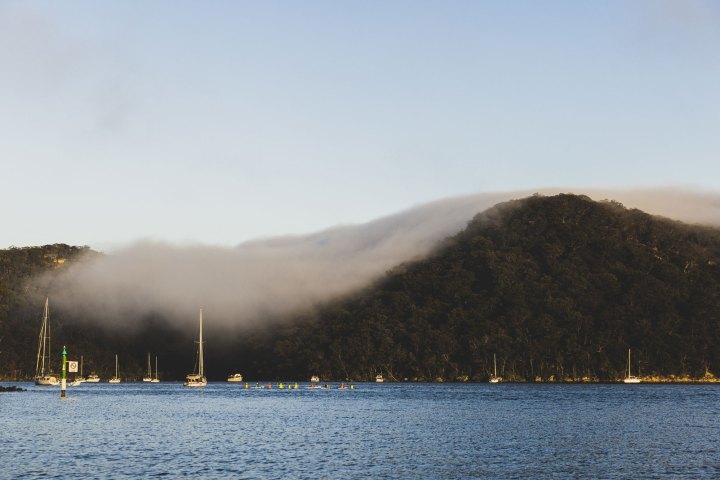 a small boat in a body of water with a mountain in the background